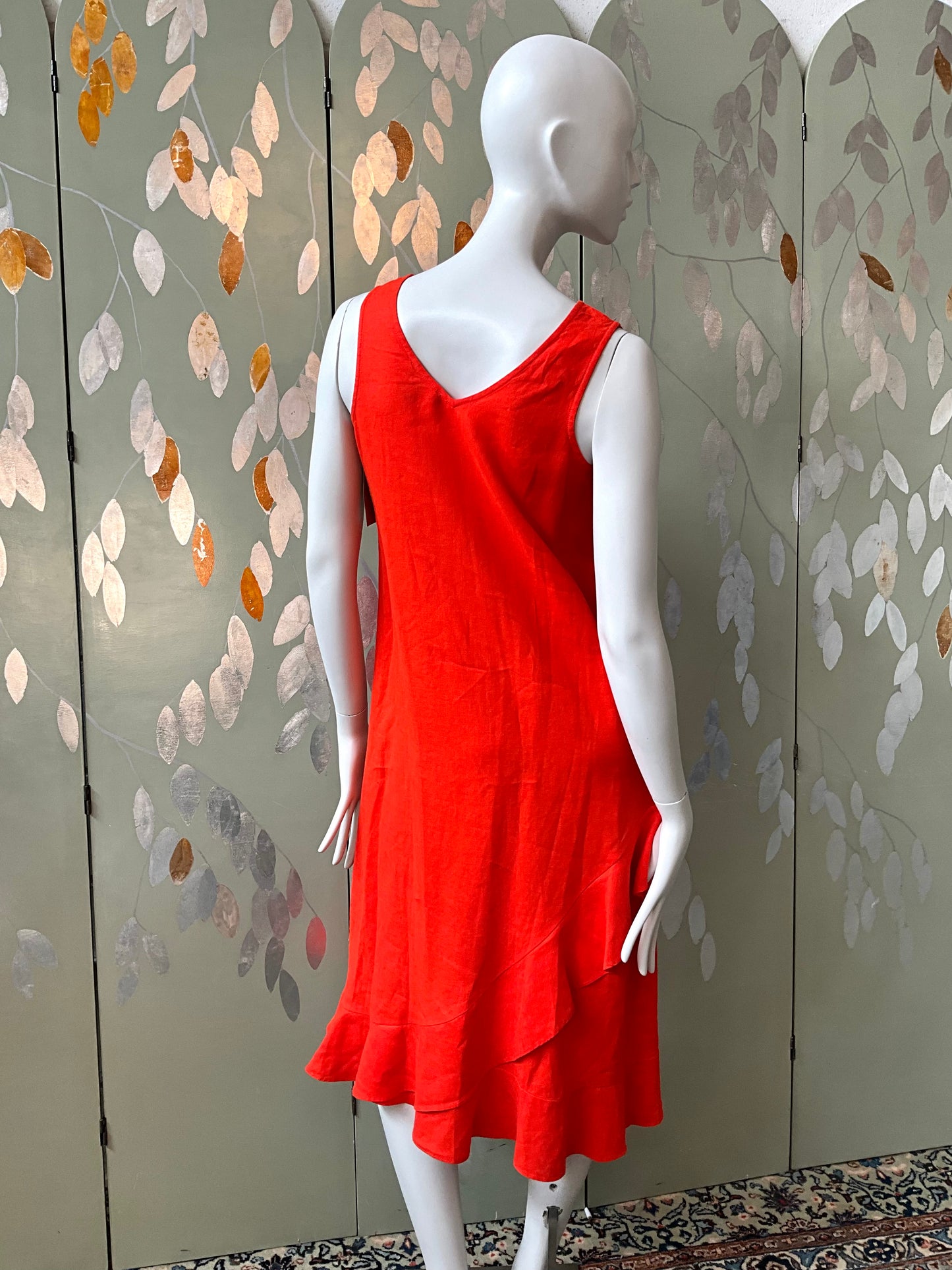 Red dress on a mannequin against a decorative wall.