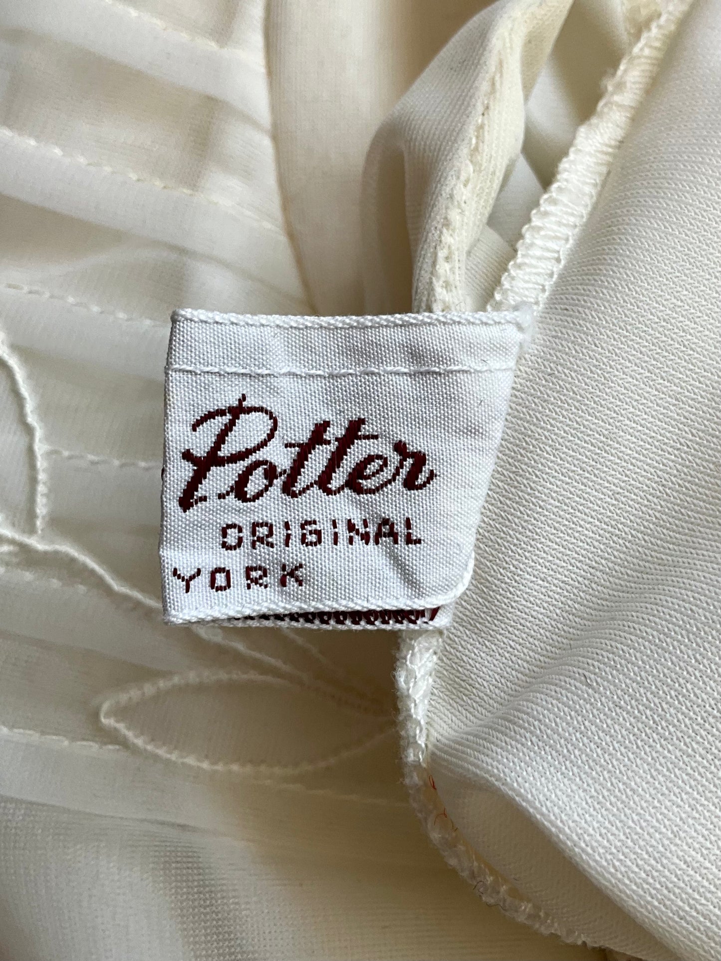 Close-up of a 'Penny Potter Original New York' label on white fabric.