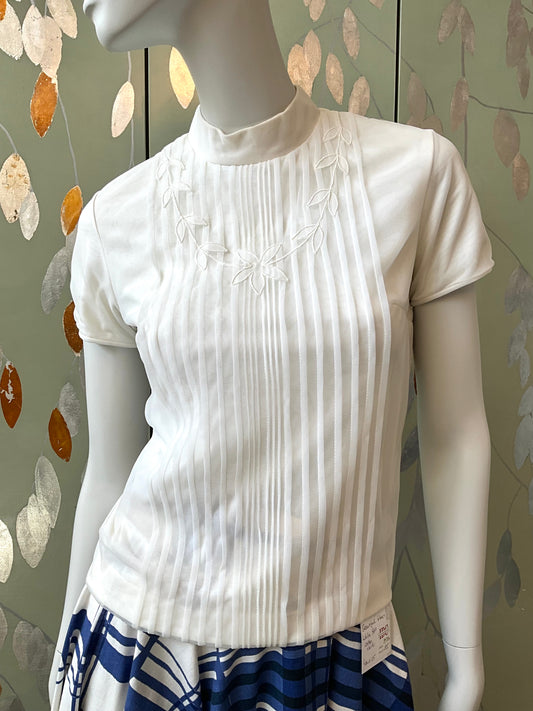 White blouse on a mannequin with a patterned background