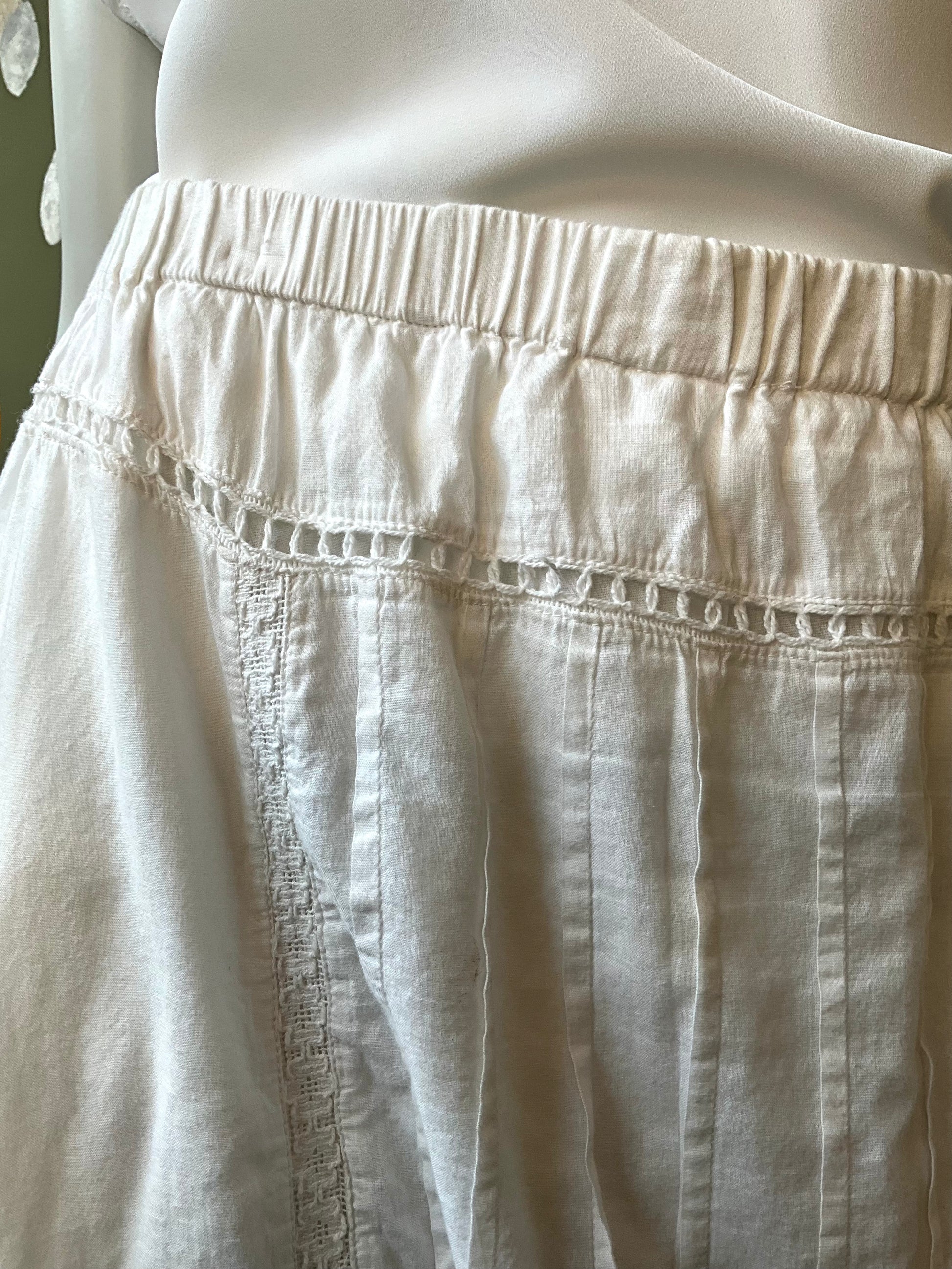 Close-up of a white skirt on a mannequin against a neutral background