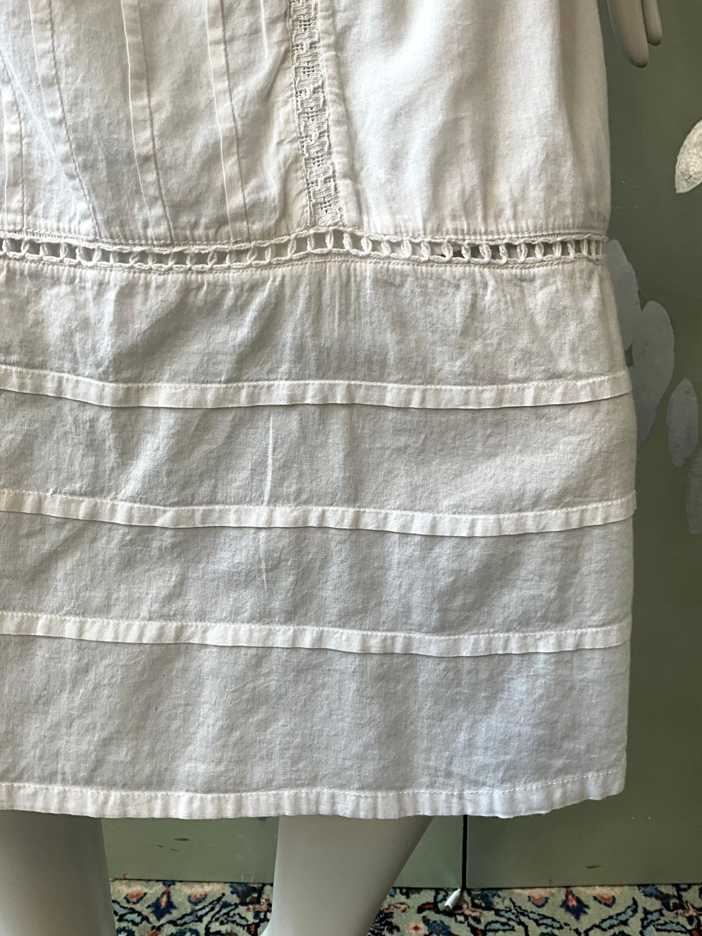 White dress on a mannequin against a green wall.