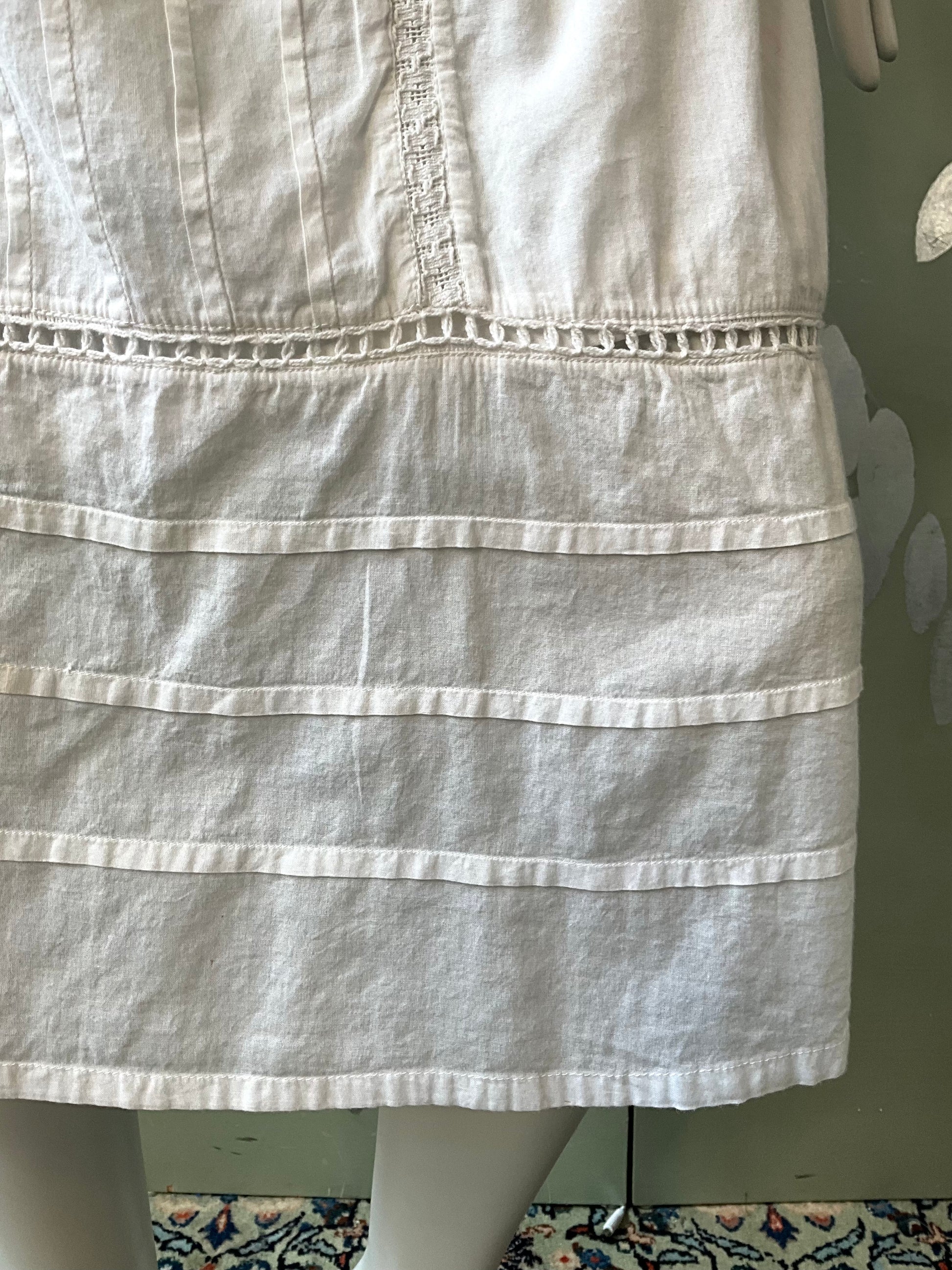 White dress on a mannequin against a green wall.