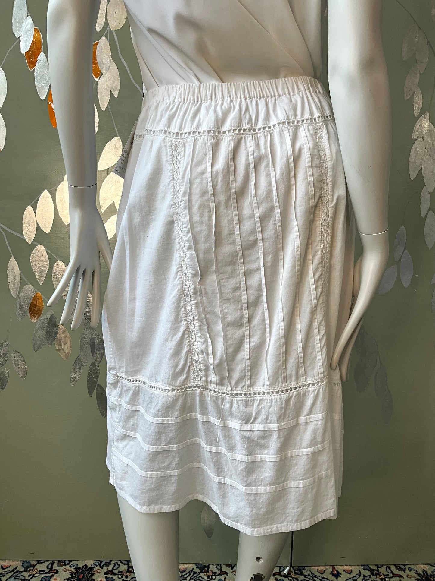 White skirt on a mannequin against a decorative wall.