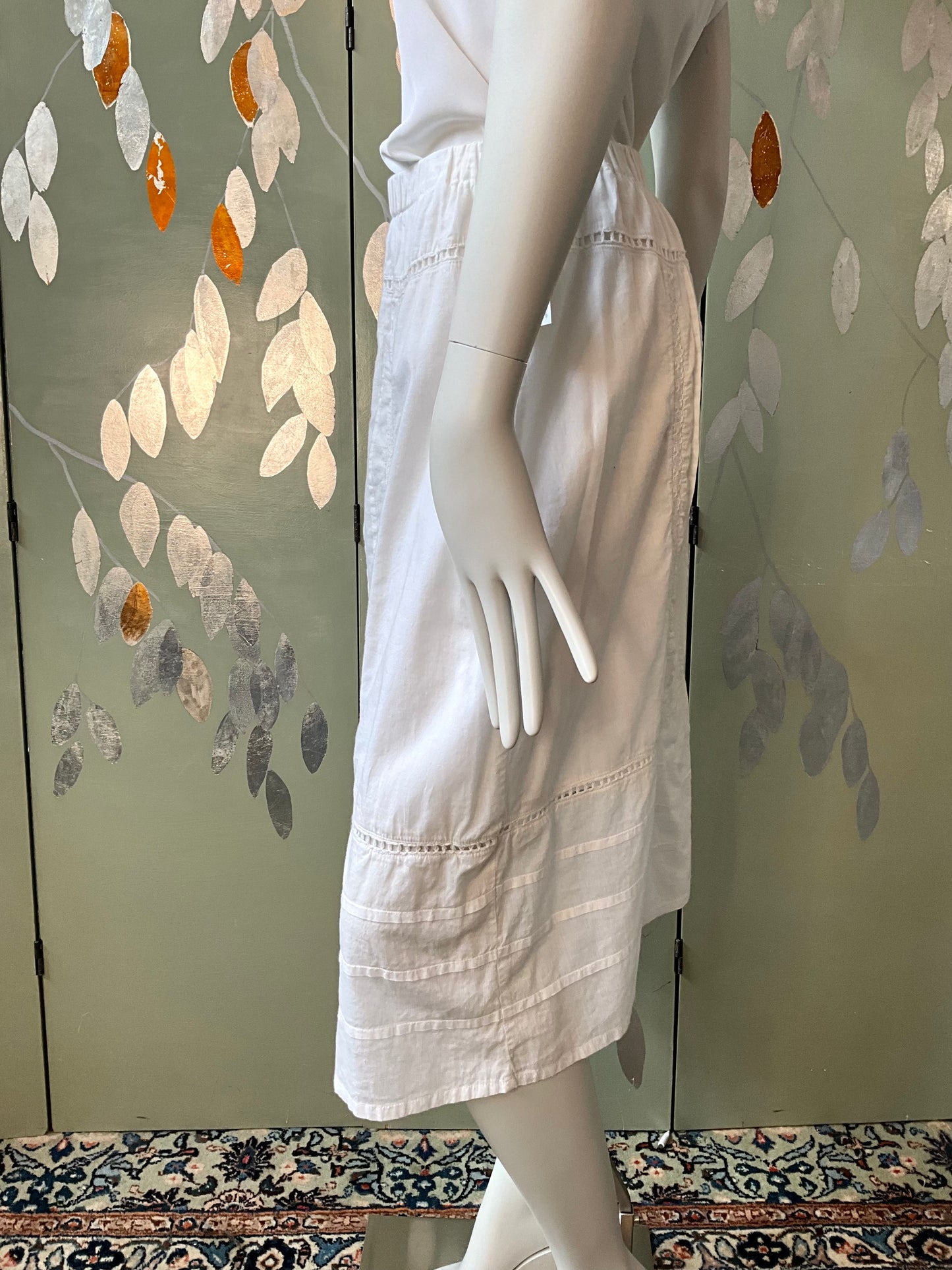 White skirt on a mannequin against a decorative wall.
