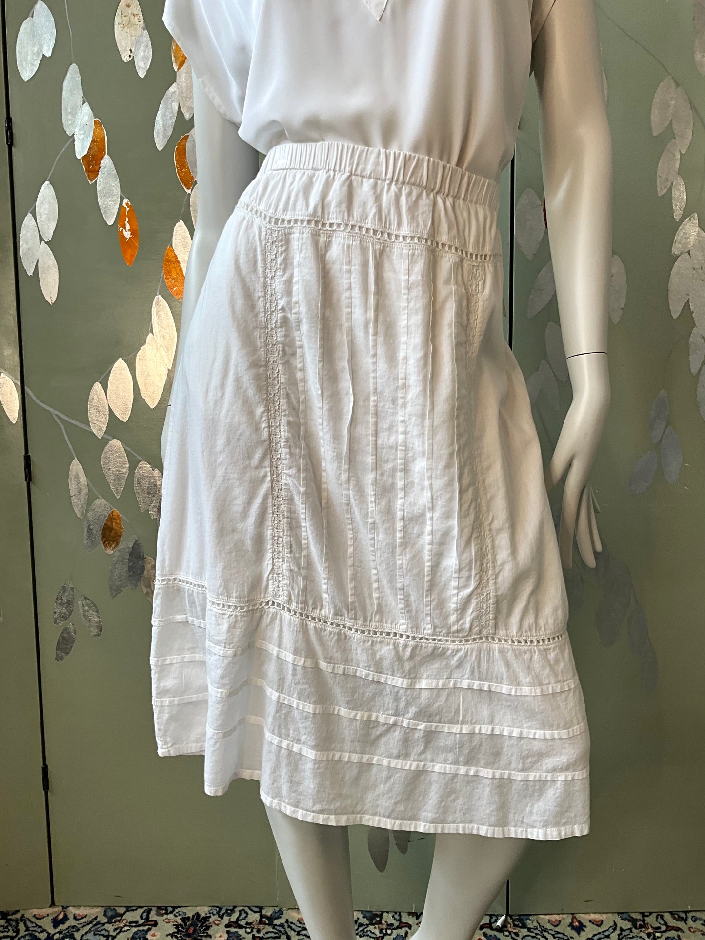 White skirt on a mannequin against a decorative wall.