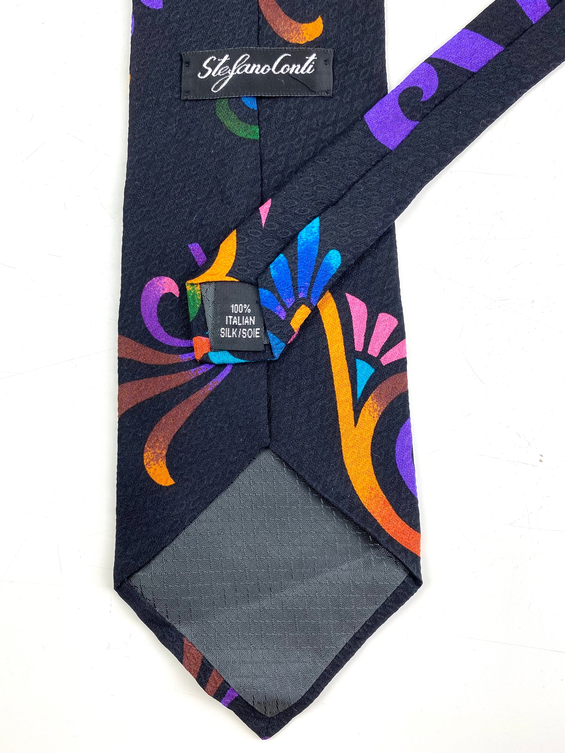 Back and labels of: 90s Deadstock Silk Necktie, Men's Vintage Purple/ Orange/ Blue Tikki Pattern Tie, NOS
