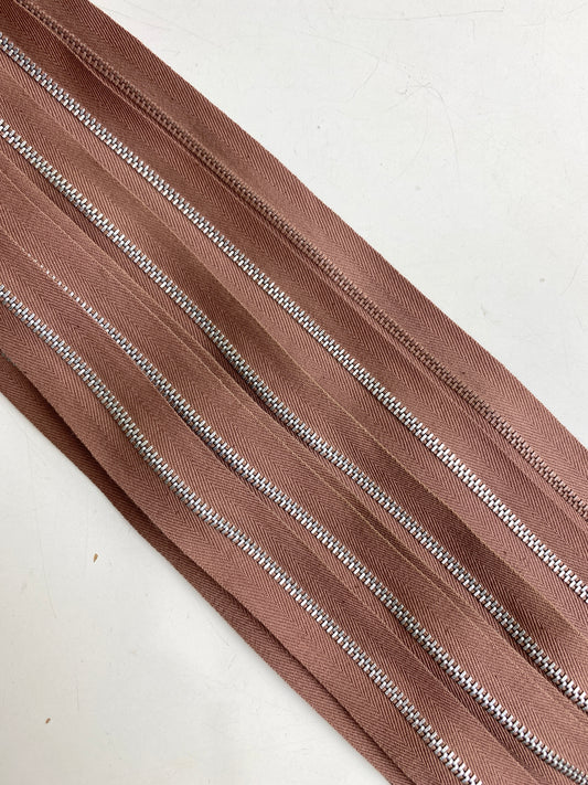 A batch line-up of brown metal vintage zippers. Ian Drummond Vintage. 