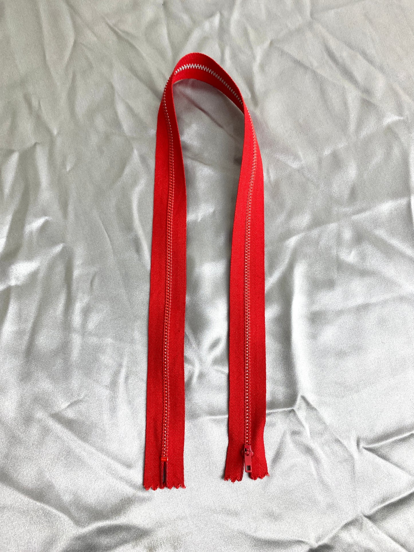 A single red metal vintage zipper. Ian Drummond Vintage.