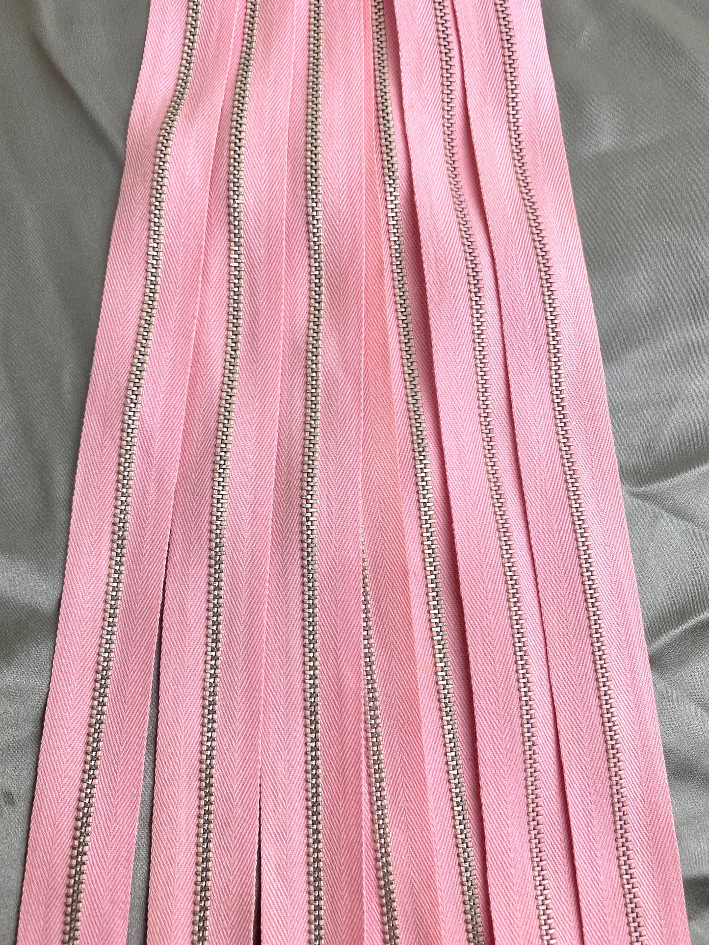 A batch of light pink metal zippers. Ian Drummond Vintage.
