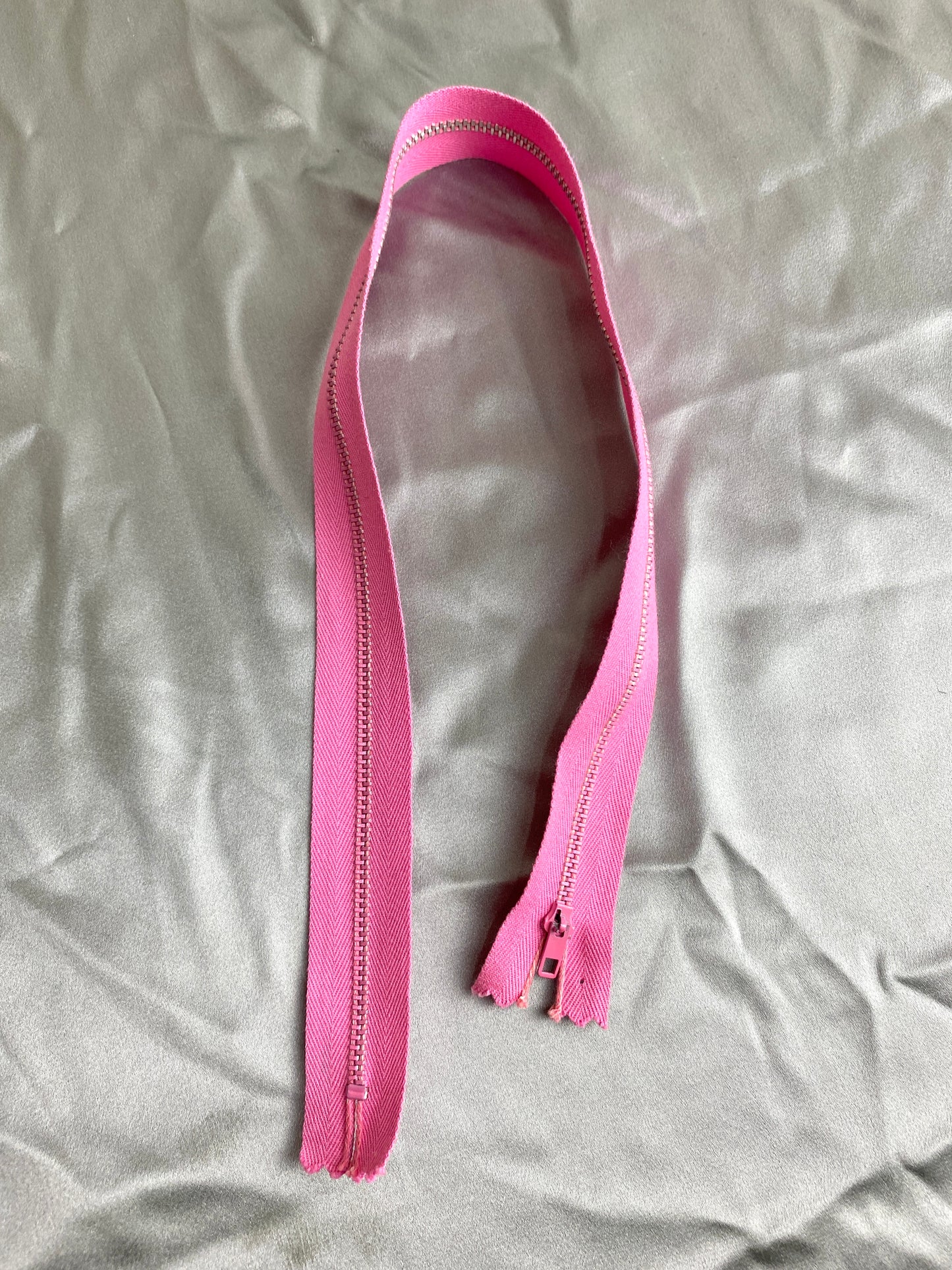 A single pink metal vintage zipper. Ian Drummond Vintage. 
