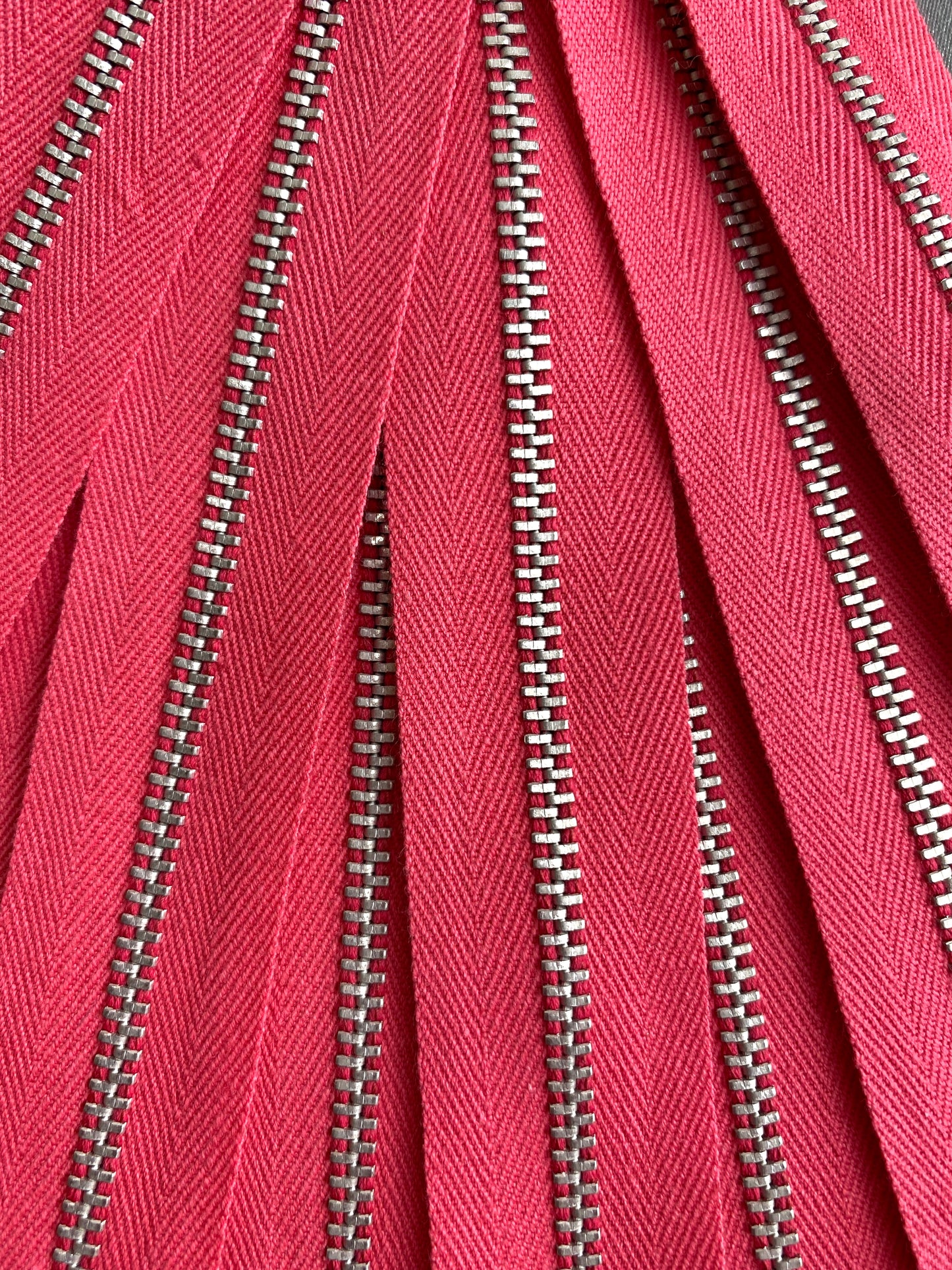 A close-up of a batch of pink metal zippers. Ian Drummond Vintage. 