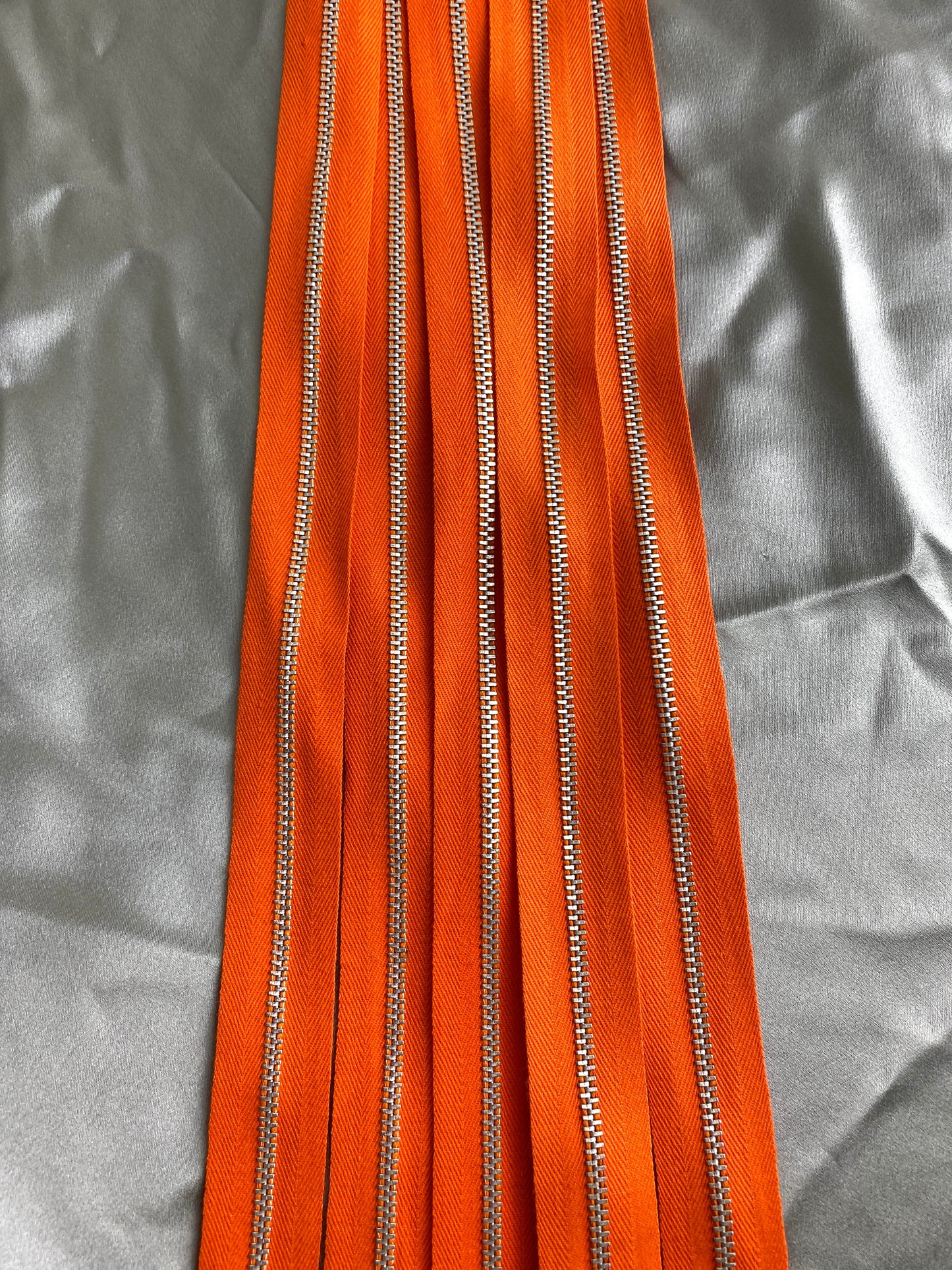 A batch of dark orange vintage metal zippers. Ian Drummond Vintage. 