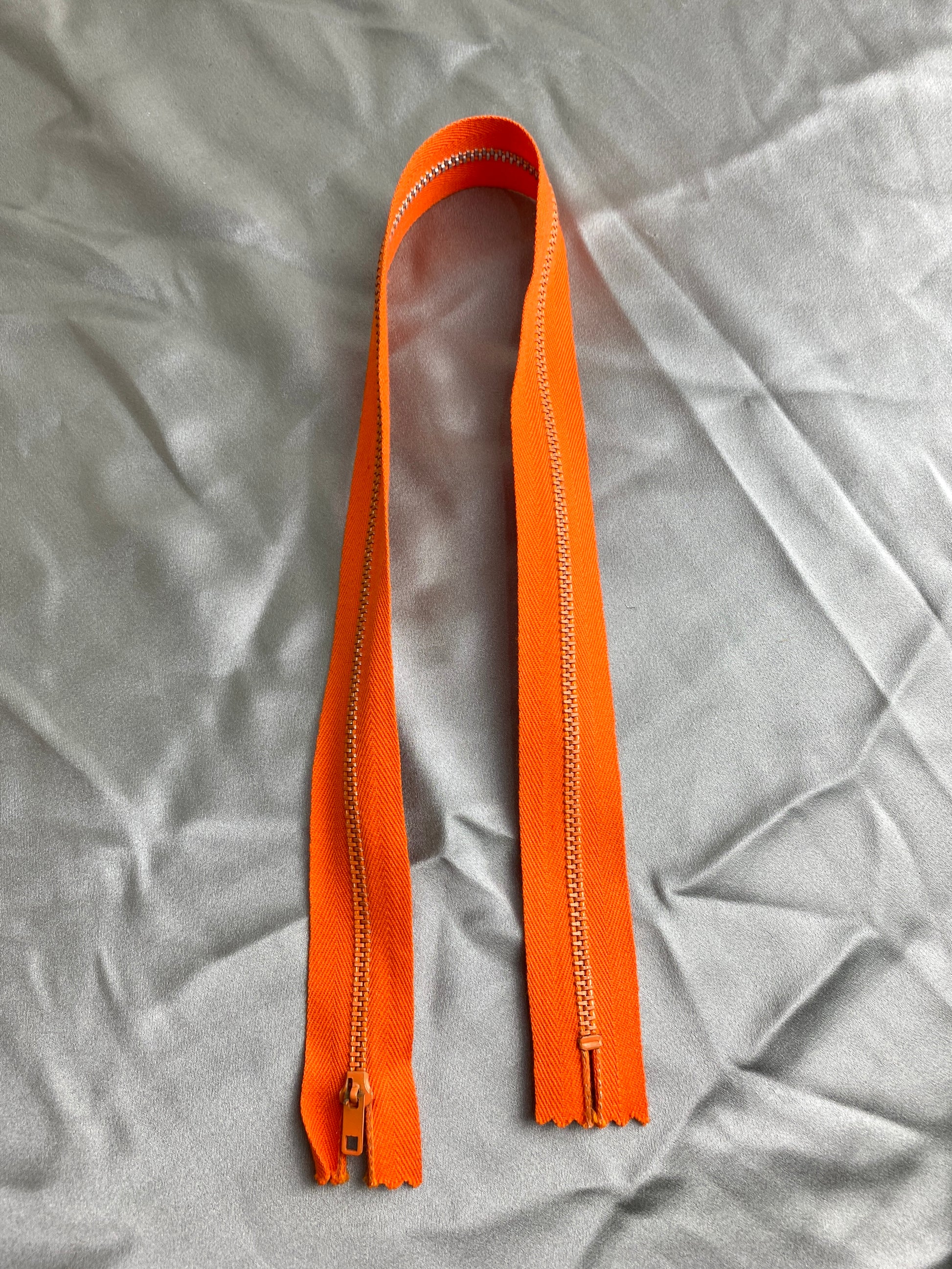 A single dark orange metal zipper. Ian Drummond Vintage. 