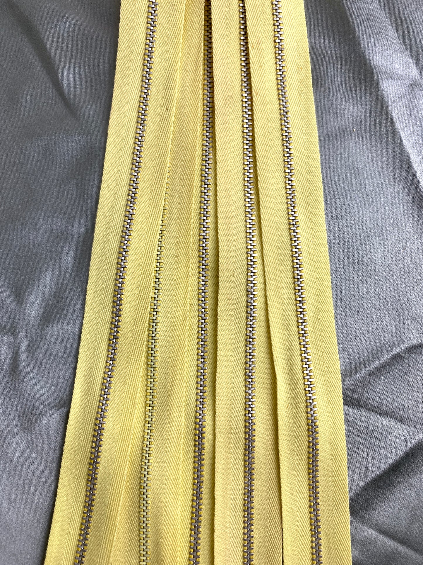Close-up of light yellow vintage metal zippers. Ian Drummond Vintage. 