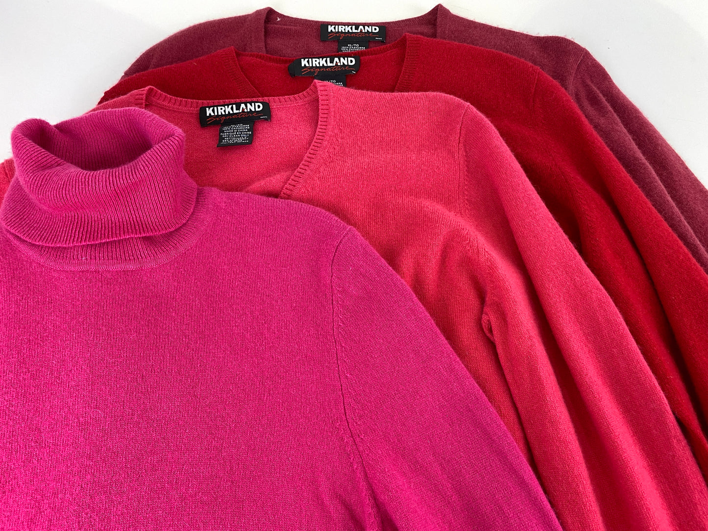4 vintage cashmere sweaters in pink and red, laying flat. Ian Drummond Vintage.