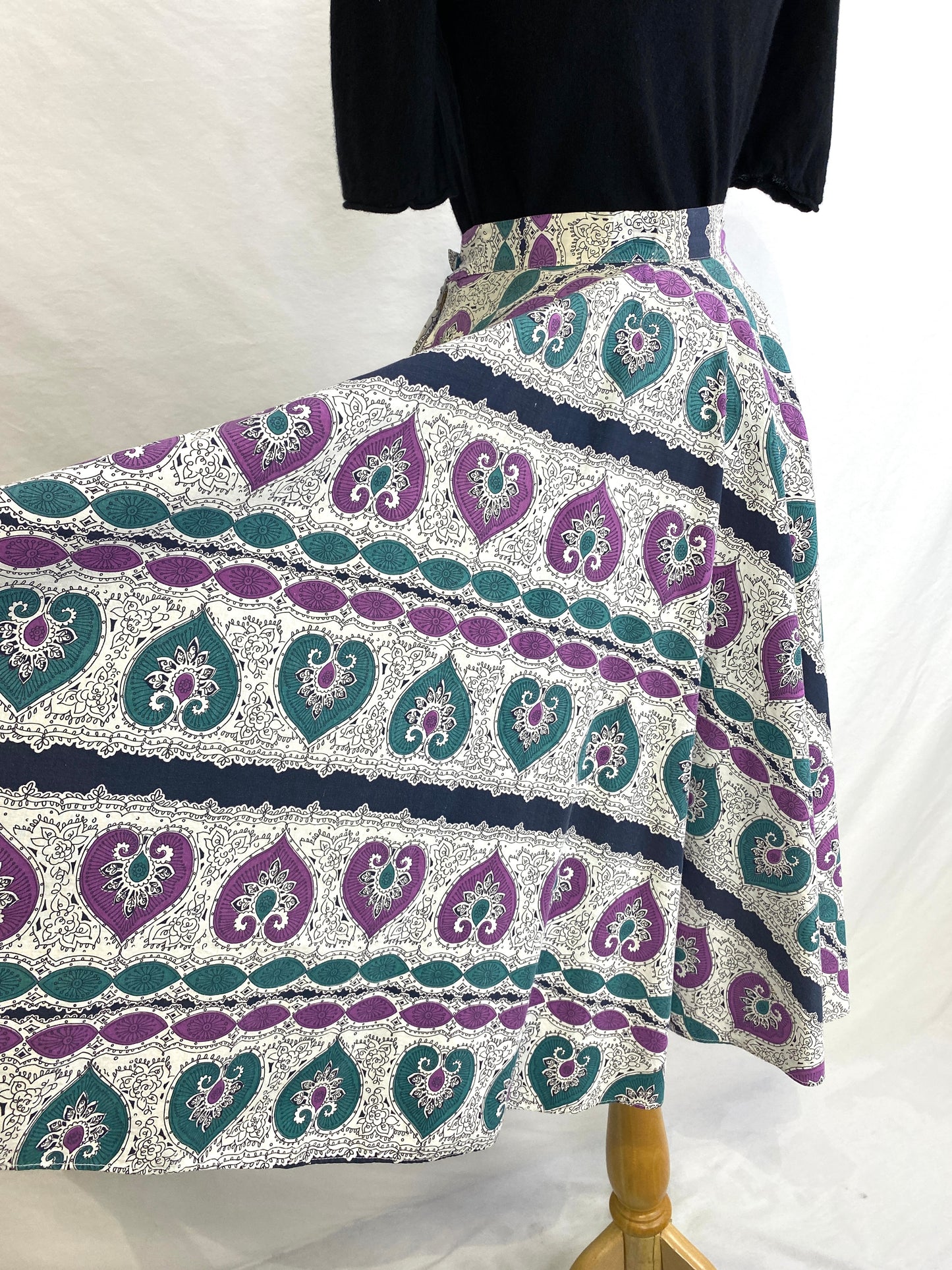 The fabric of a 50s print circle skirt is held out for a clearer view of the print and width of the skirt. Ian Drummond Vintage. 