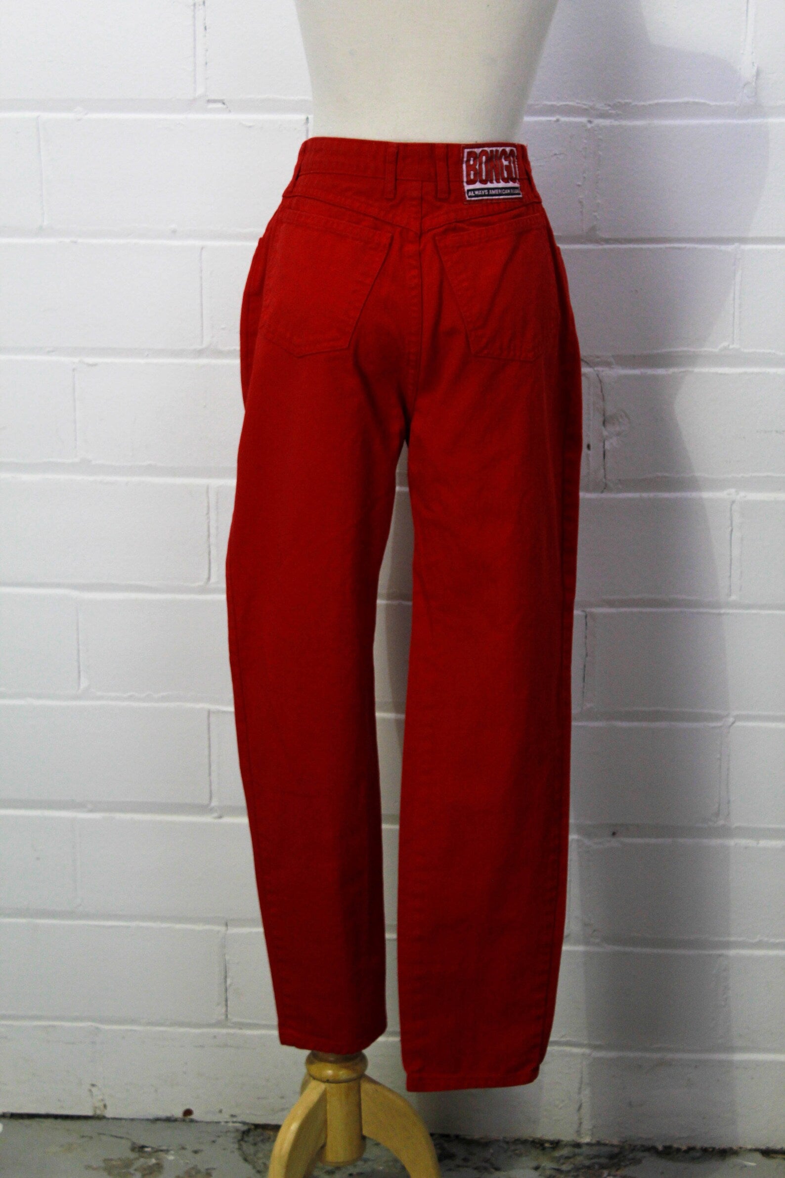 Perfect 80s red cotton high waisted denim jeans by Bongo. They have a 5 pocket design, and the Bongo logo on the back waist that reads "Always American Made". 