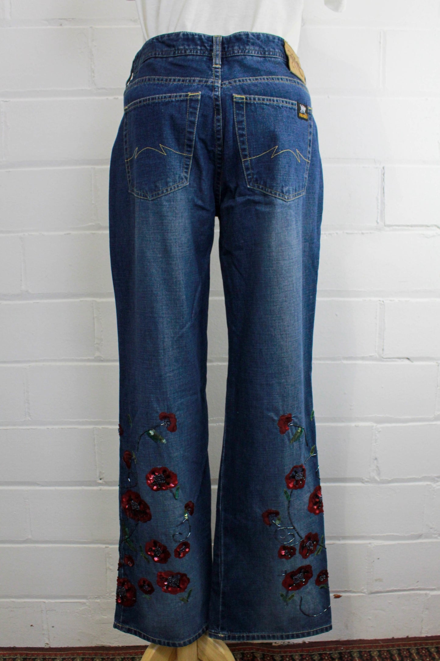 back of womens blue jeans with sequinned flower embellished legs