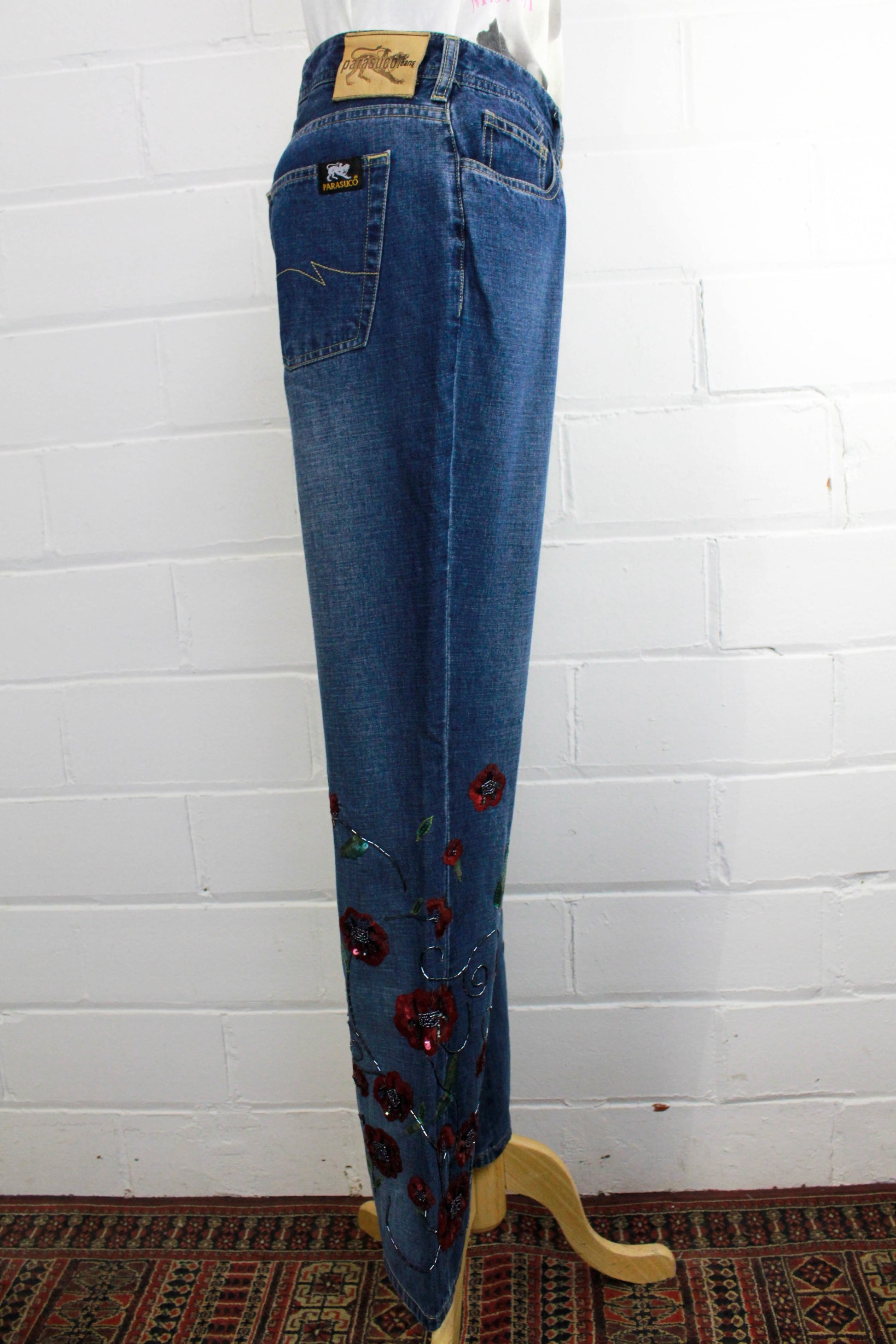 side view of womens blue jeans with flower embellished legs