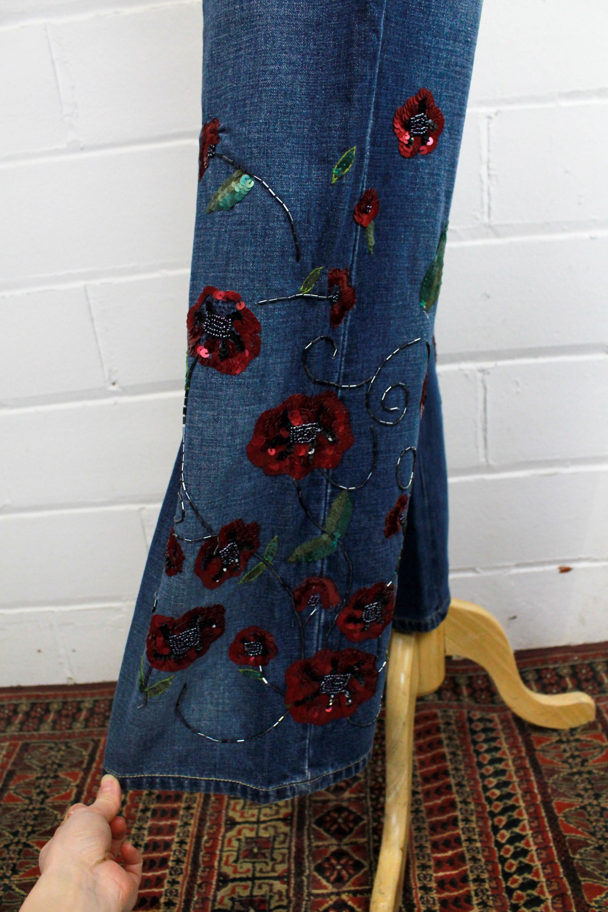 close up of sequinned flowers on flared legs of jeans